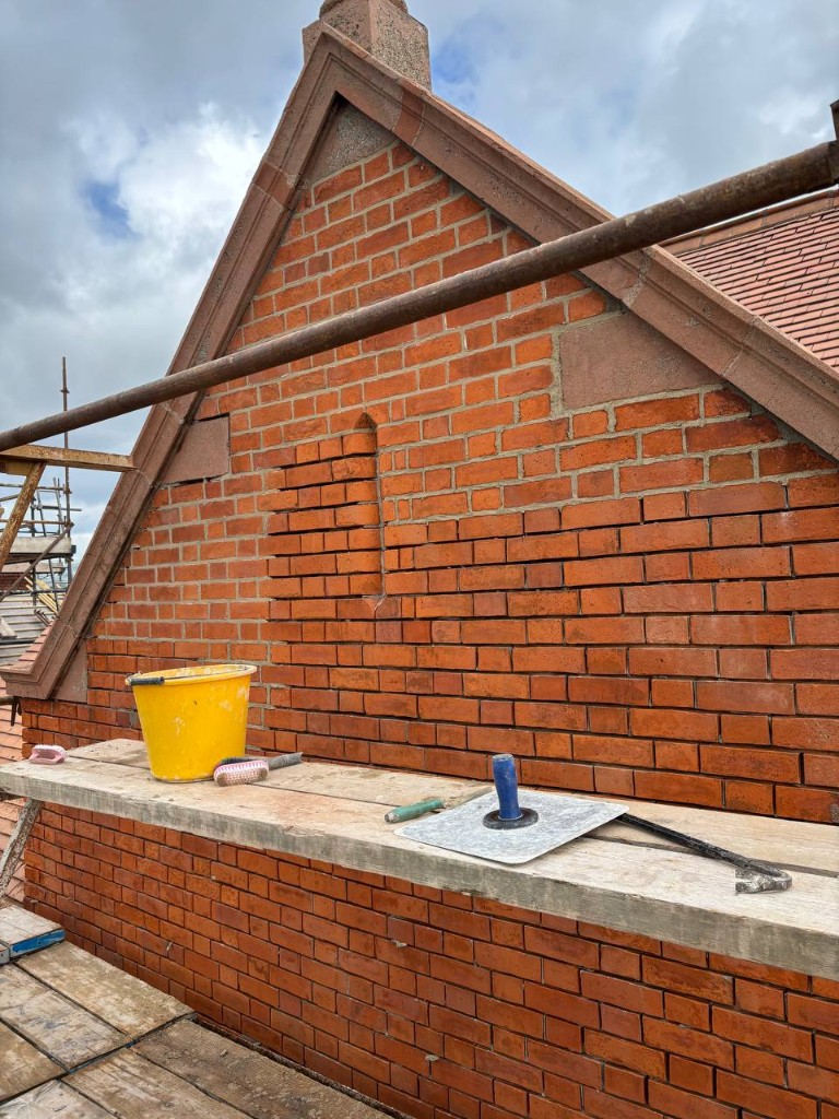 Brick repointing in progress on a Dublin gable with scaffolding and tools