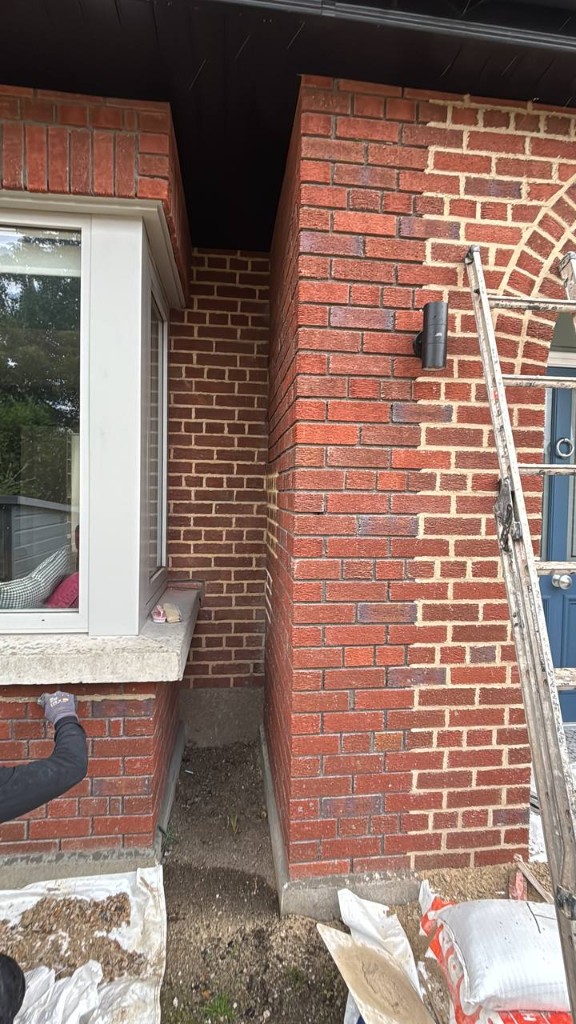 Brick pillar repointing in progress showing fresh mortar beside old joints