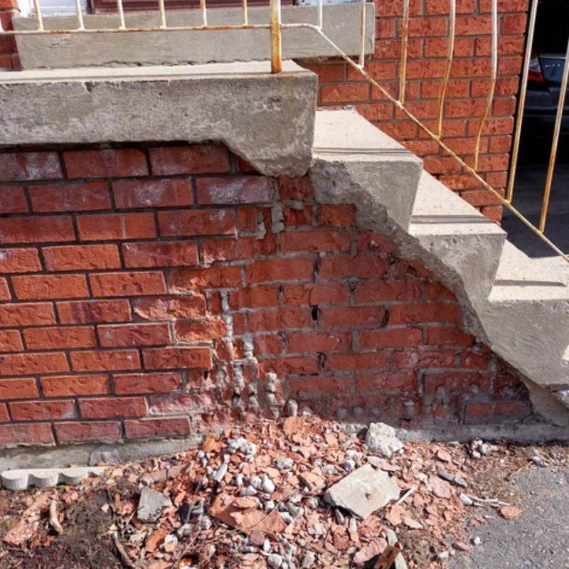 Spalling brick under concrete stairs